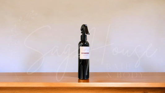 Black spray bottle with a label, on a wooden surface against a white textured wall.