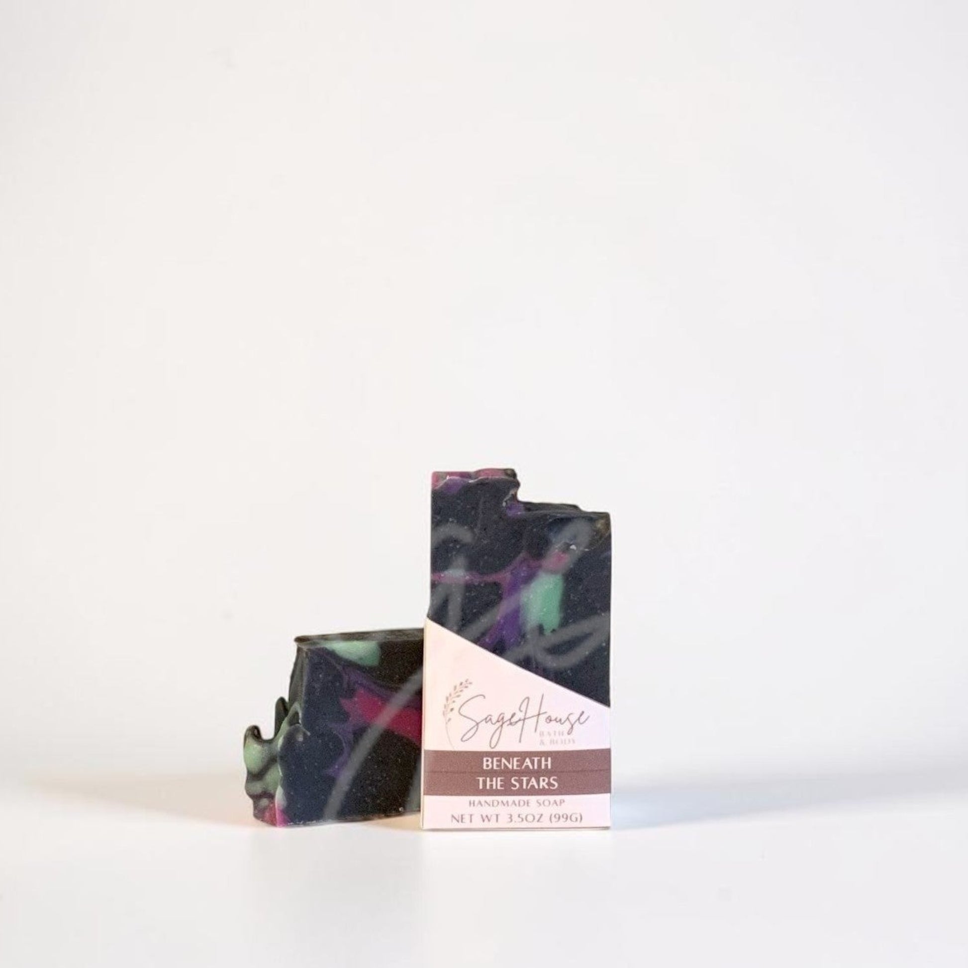 A dark bar of soap with a label, standing on a white surface against a white background.