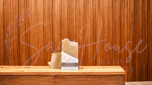 A tan bar of soap in a white labeled box, on a wood surface.