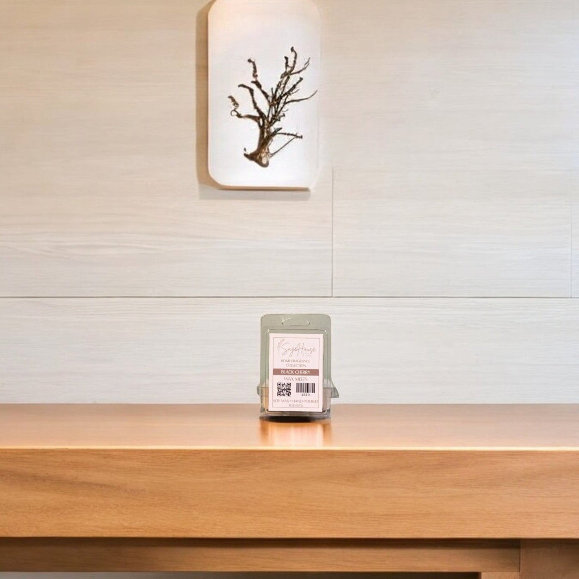 A clear clamshell container holding 6 wax melt cubes with a label on top, placed on a wooden surface against a wooden background.