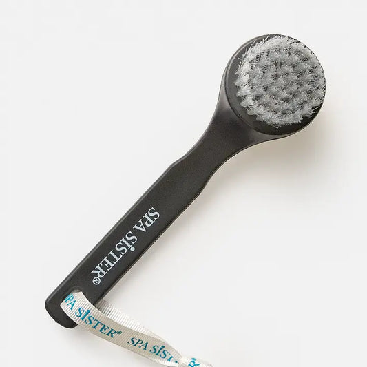 A black facial cleansing brush with string. On white background