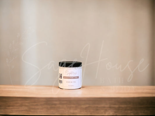 A jar of Black Raspberry Vanilla Body Butter placed on a wooden surface with a neutral background.