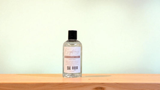 Bottle of "black raspberry vanilla" body wash on a wooden surface with a light background