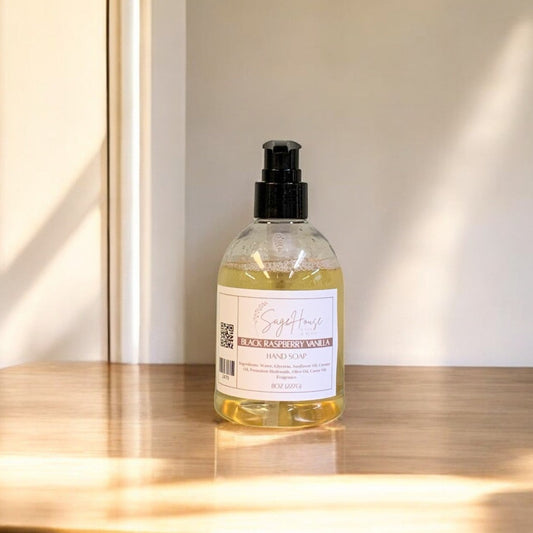 A clear plastic bottle of hand soap with a black cap, placed on a wooden surface with natural lighting.