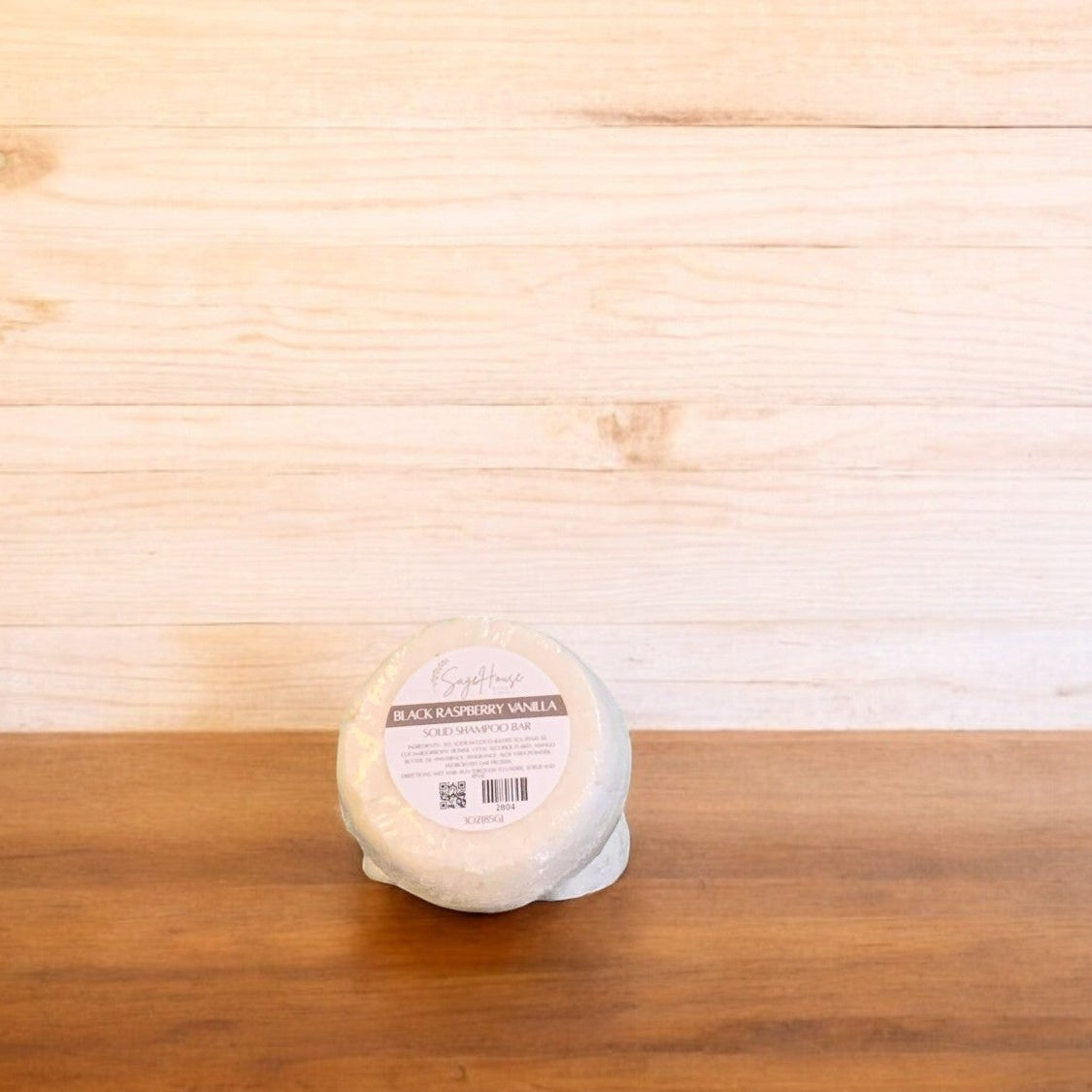 two shampoo bars, one in front of the other. placed on a wood surface with a light wood surface in the background