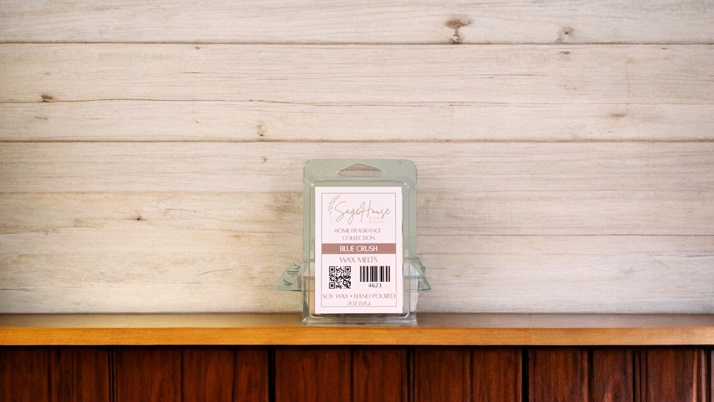 A clear clamshell container holding 6 wax melt cubes with a label on top, placed on a wooden surface against a wooden background.