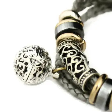bracelet with braided gray leather and silver and black beaded accents, with lava bead inside of silver ball attached.