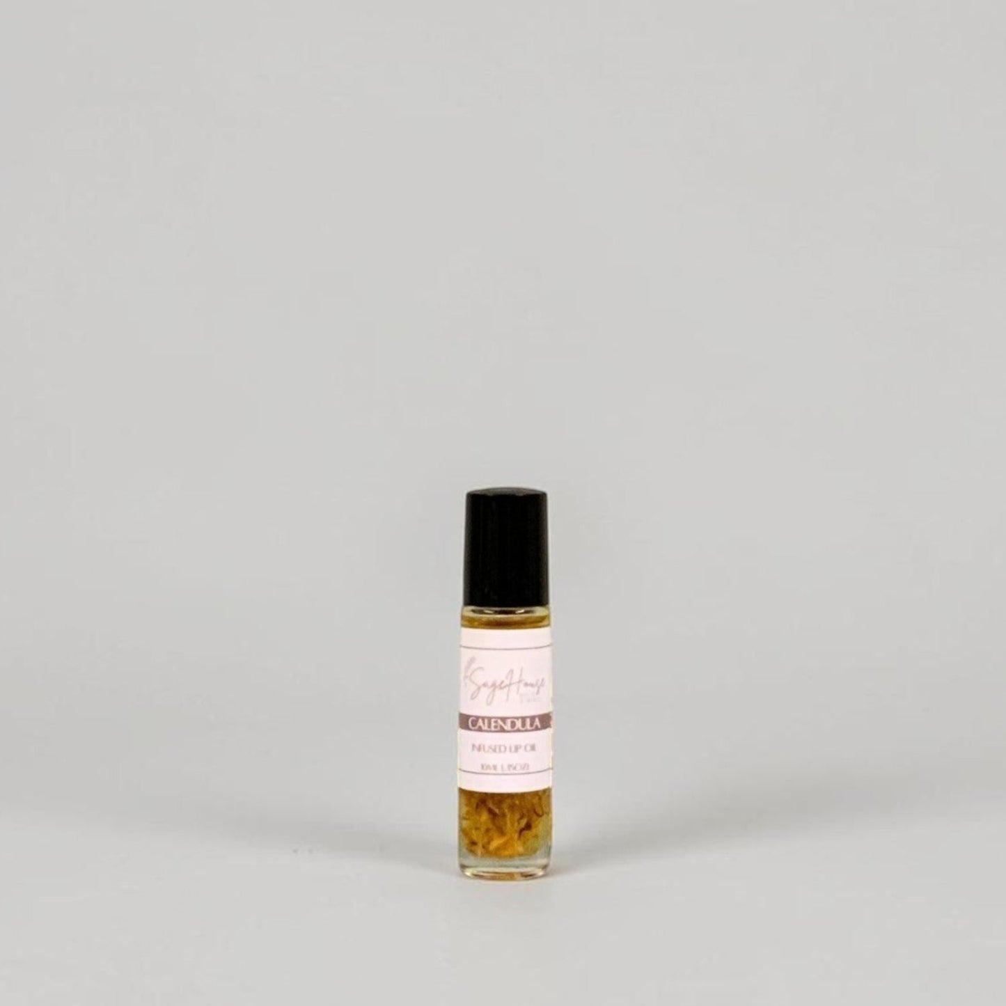 A small glass roller bottle with a black cap and a white label, standing on a light gray background.