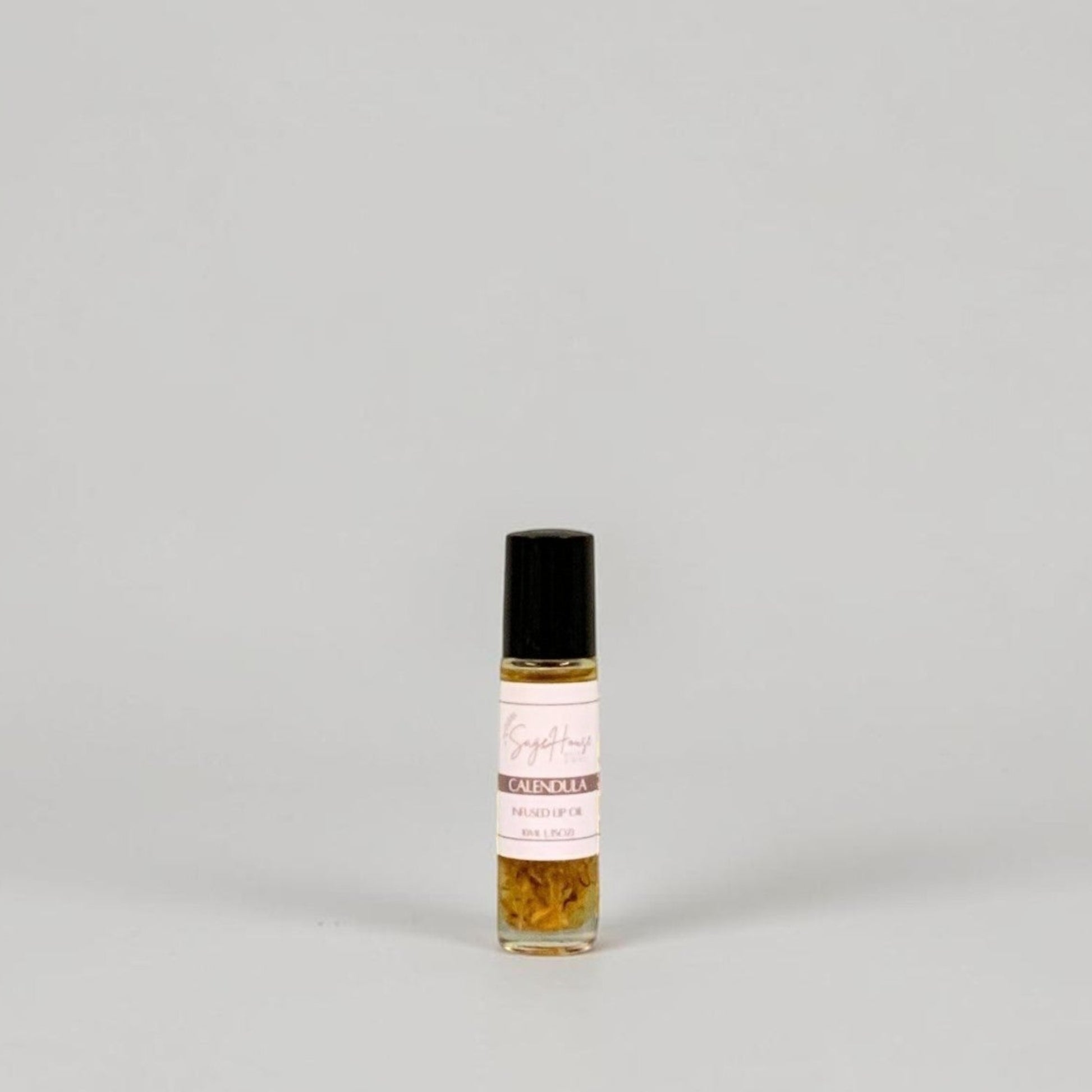 A small glass roller bottle with a black cap and a white label, standing on a light gray background.