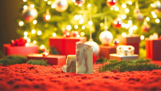 A tan colored bar of soap with accents of orange and brown, on a red carpet with a christmas background