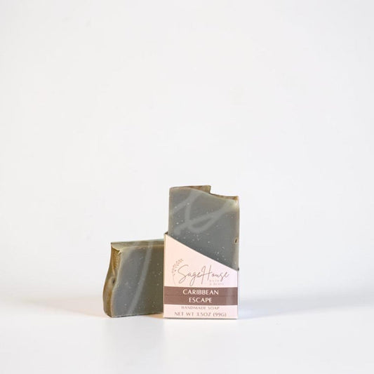 Two rectangular bars of soap with a swirled gray and olive-green marbled pattern, standing upright next to their pink paper packaging sleeve on a clean white background.