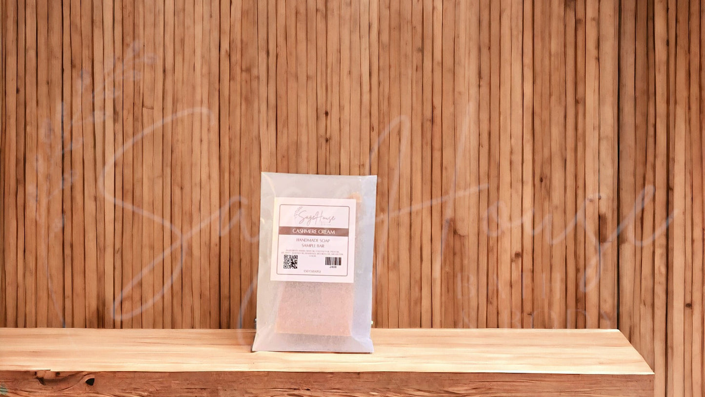A sample bar of soap in a frosted glassine bag with a label. on a wood surface.