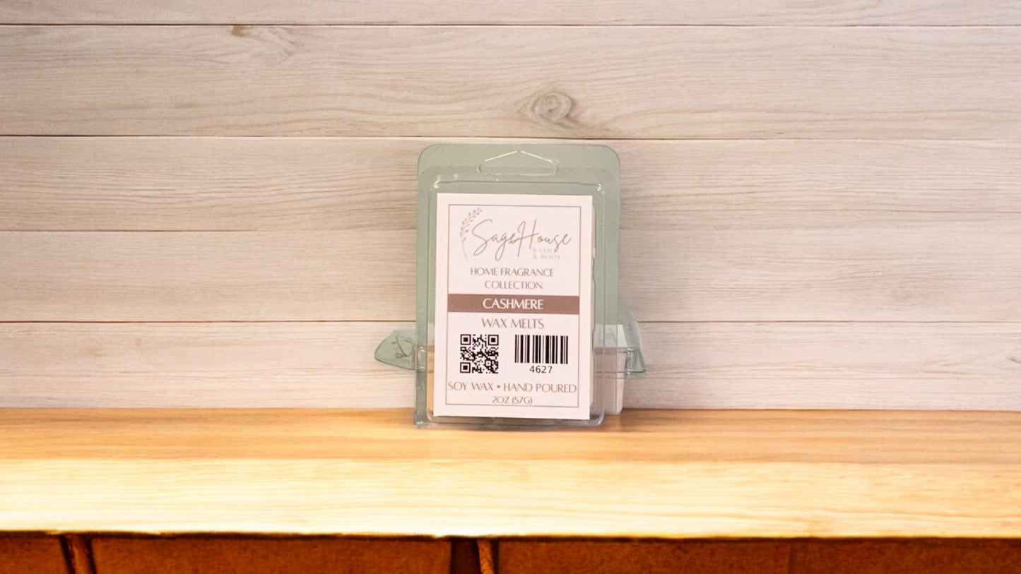 A clear clamshell container holding 6 wax melt cubes with a label on top, placed on a wooden surface against a wooden background.