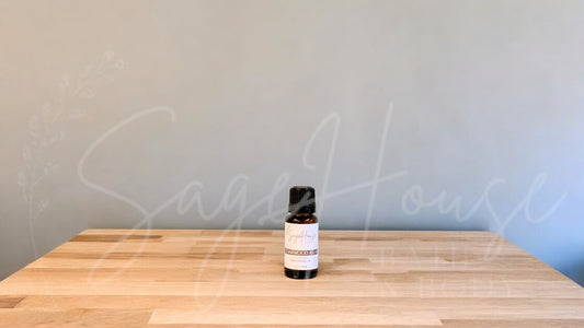 A small bottle of cedarwood essential oil is placed on a wooden surface with a plain background.