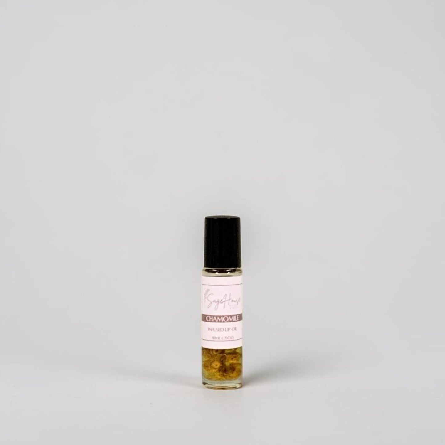 A small glass roller bottle with a black cap and a white label, standing on a light gray background.