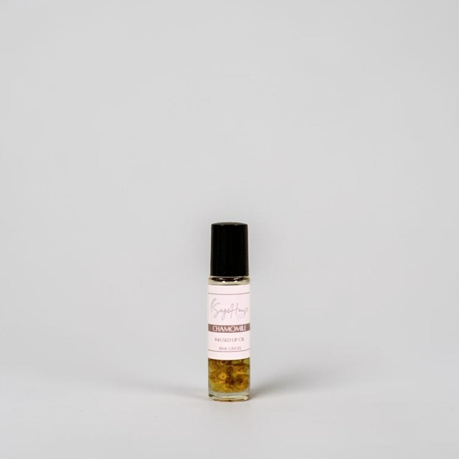 A small glass roller bottle with a black cap and a white label, standing on a light gray background.