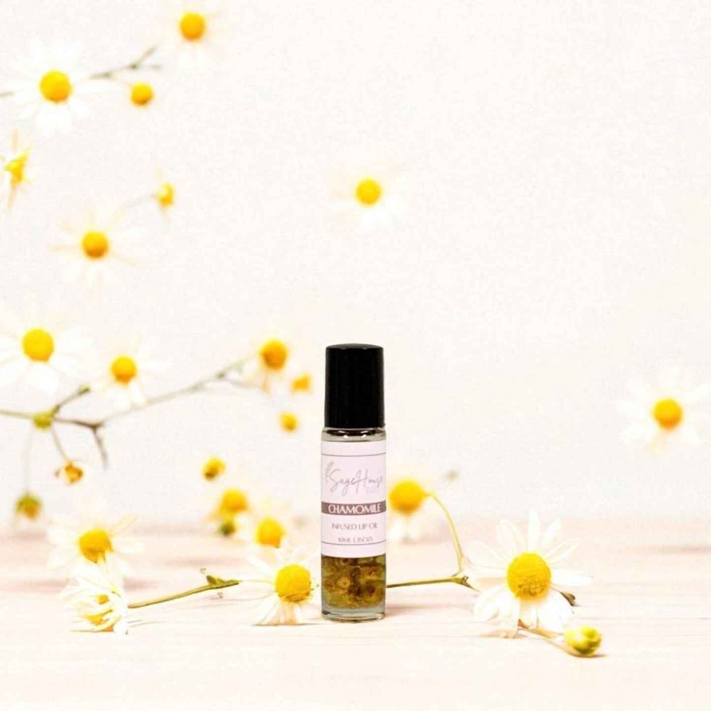 Small bottle of lip oil with yellow flowers surrounding, on a light background