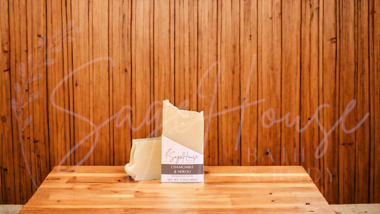 A tan bar of soap in a white labeled box, on a wood surface.