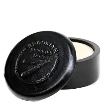 A black wood shave bowl with a lid, polished and sealed with a brand stamp on the front.