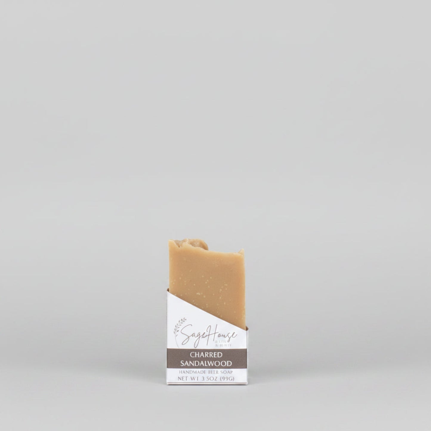 A tan bar of soap in a white labeled open box. on a wood surface.