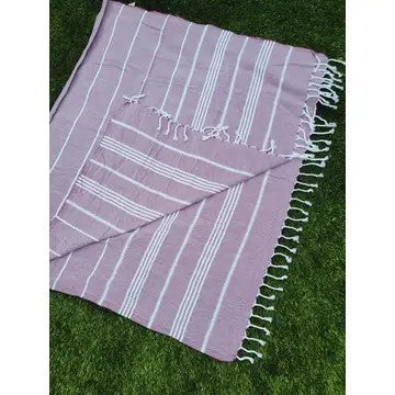 Cherry colored Turkish cotton towel, folded onto itself, on a grass background.