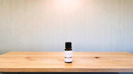 A small bottle of citrus blend essential oil is placed on a wooden surface with a plain background.