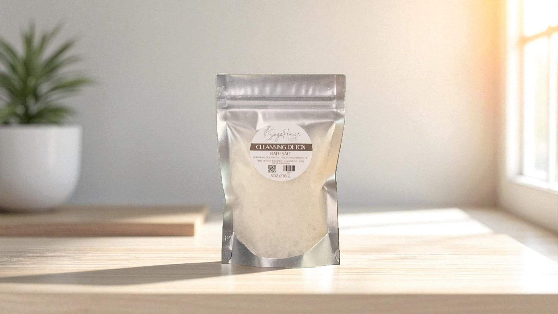 Silver packaging with a clear window of white salt labeled "cleansing detox" on a wood surface.