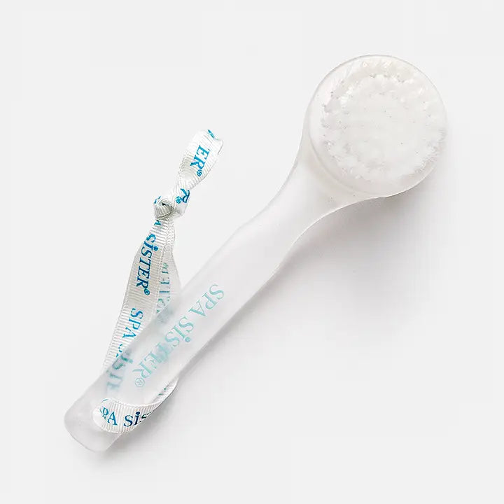 A clear facial cleansing brush with string. On white background