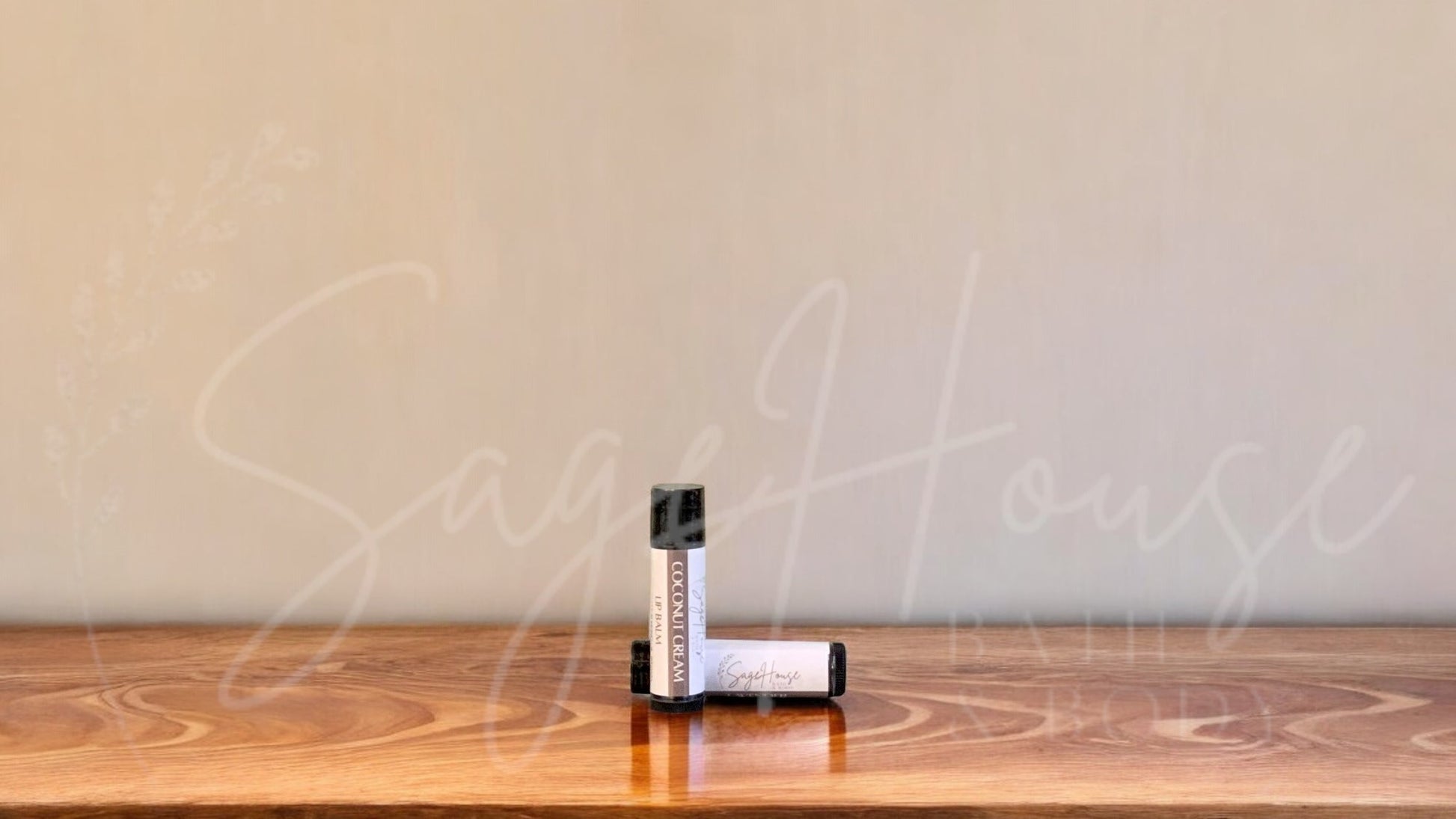 A tube of coconut cream lip balm placed upright with a tube lying behind it, on a wooden surface.