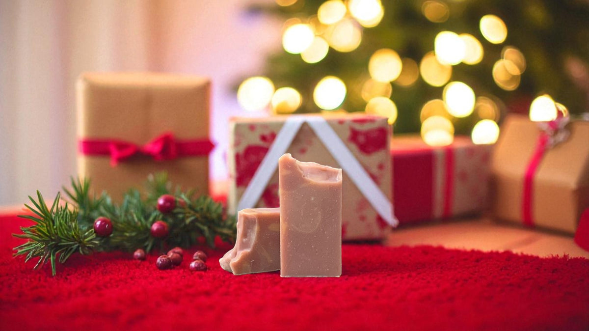 A light cranberry colored bar of soap with peach colored accents, with Christmas decor in the background
