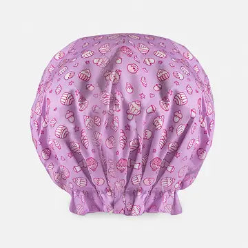 A pink shower cap with cupcake and desert print. On a white background