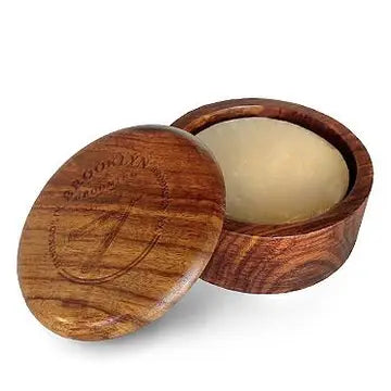 A dark wood shave bowl with a lid, polished and sealed with a brand stamp on the front.
