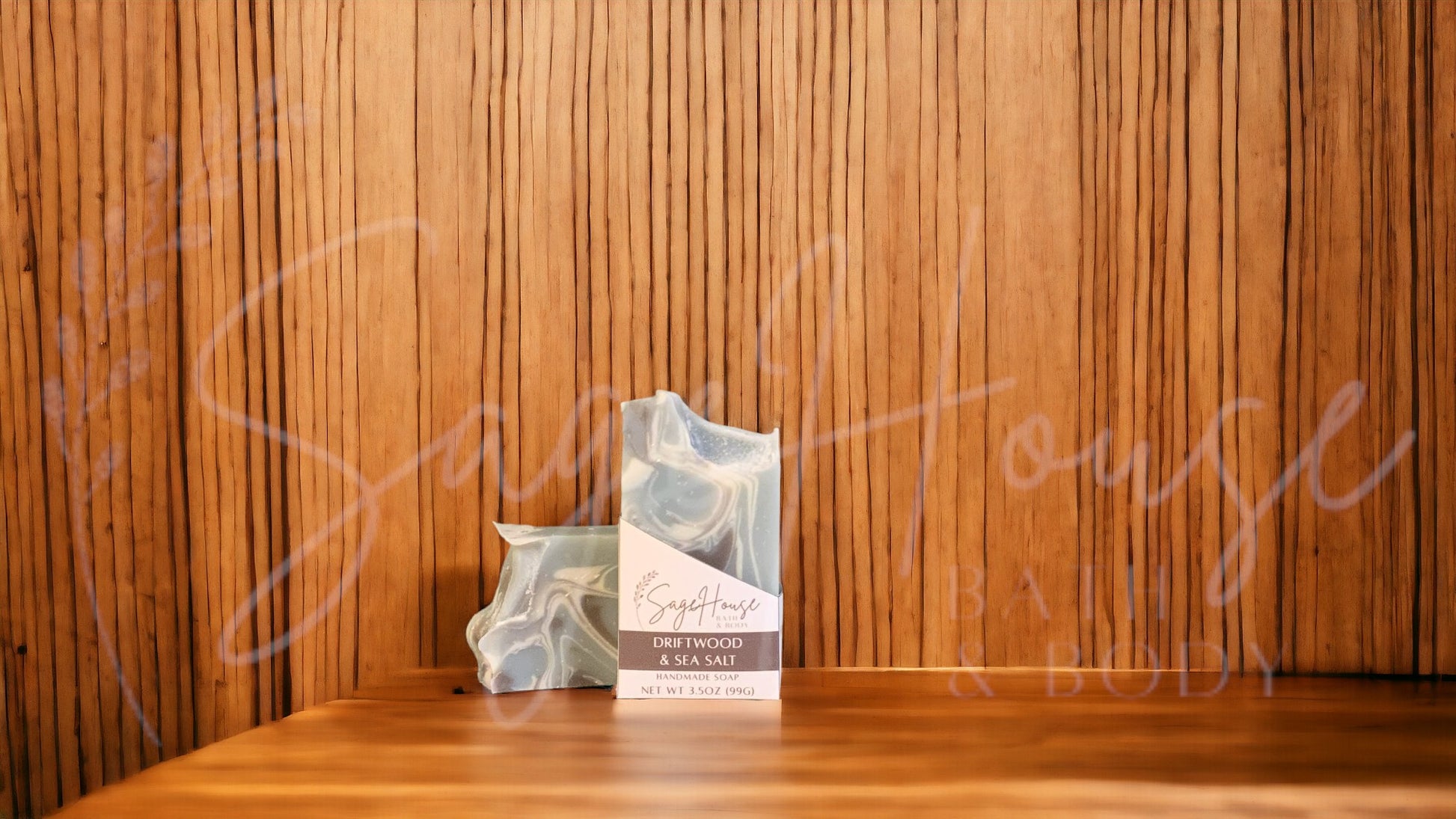 A light blue colored bar of soap with accents of brown and white, in a white labeled box, on a wood surface.