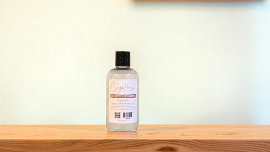 Bottle of "eucalyptus spearmint" body wash on a wooden surface with a light background