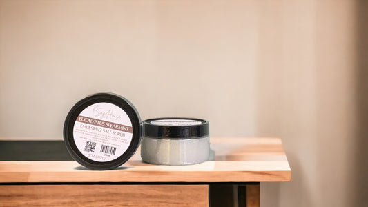 A jar of Eucalyptus Spearmint Salt Scrub with black lid. placed on a wooden surface.