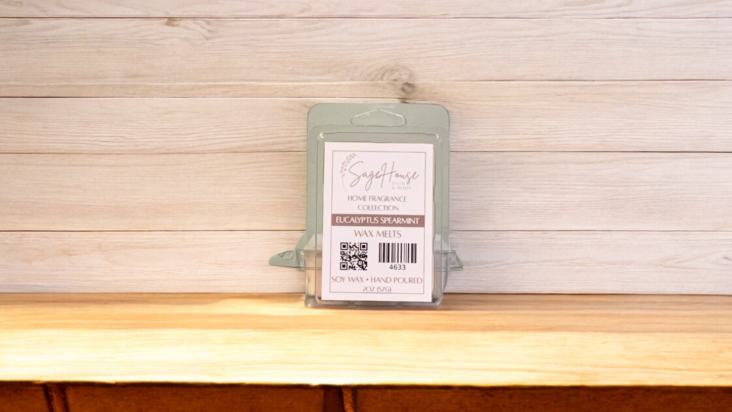 A clear clamshell container holding 6 wax melt cubes with a label on top, placed on a wooden surface against a wooden background.