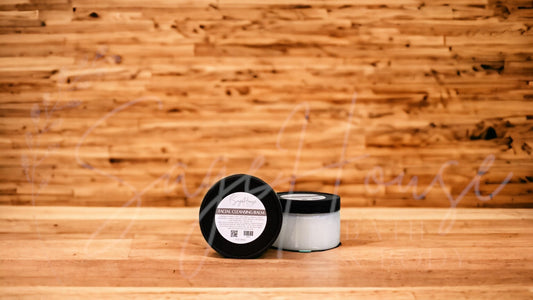 A jar of cleansing balm with a label, placed on a wooden surface with a wooden background.