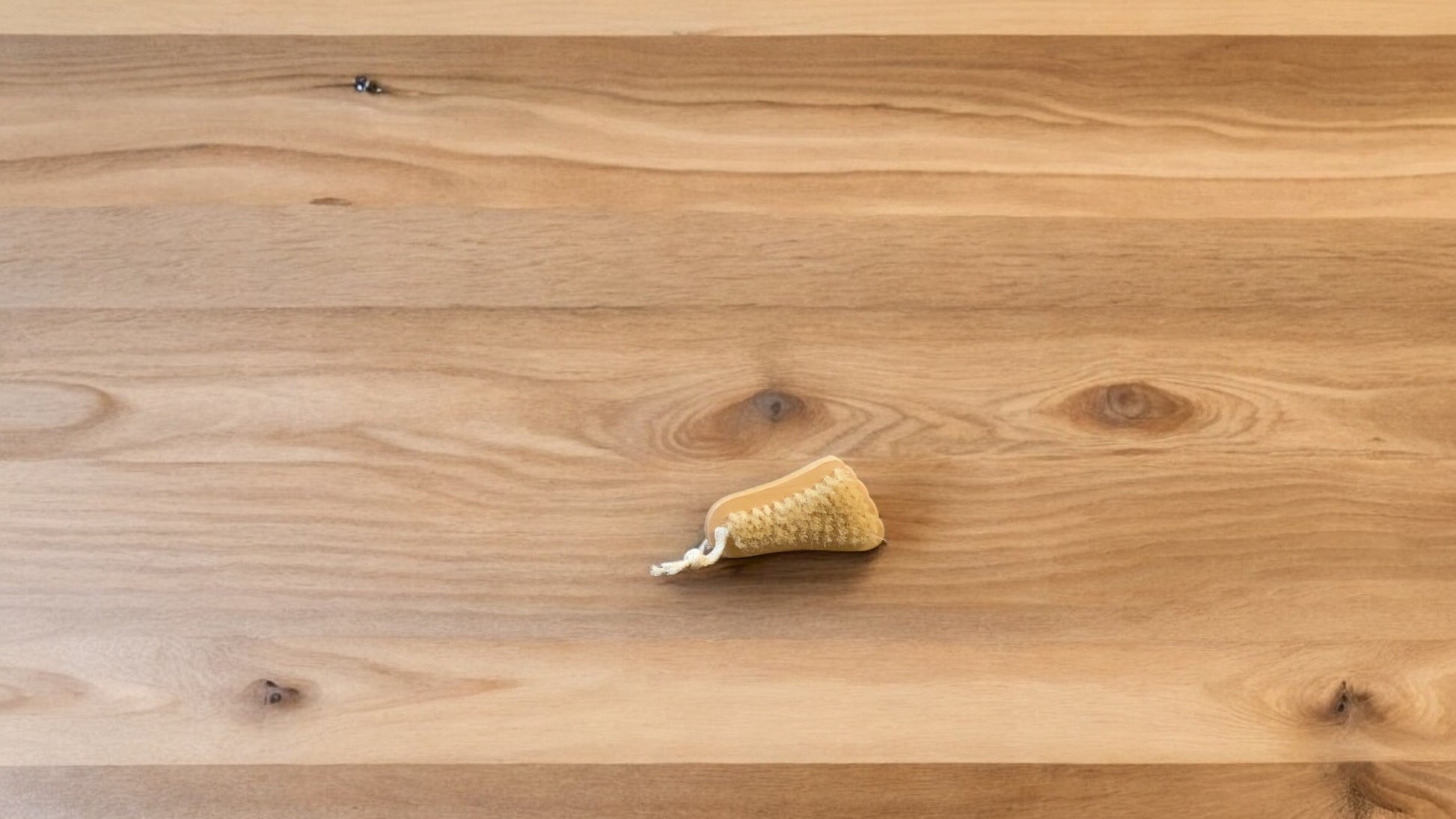 a toenail foot shaped brush sitting on a wooden surface