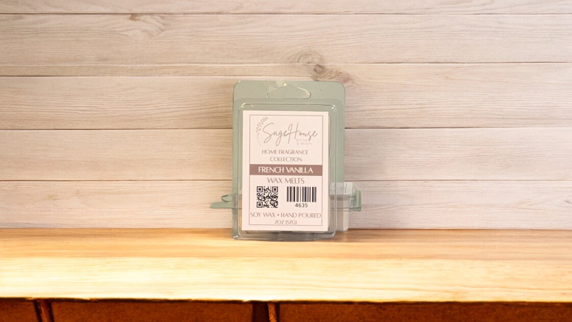 A clear clamshell container holding 6 wax melt cubes with a label on top, placed on a wooden surface against a wooden background.