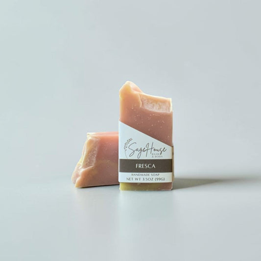 A labeled bar of soap sitting in front of a matching bar of soap. On a white background.