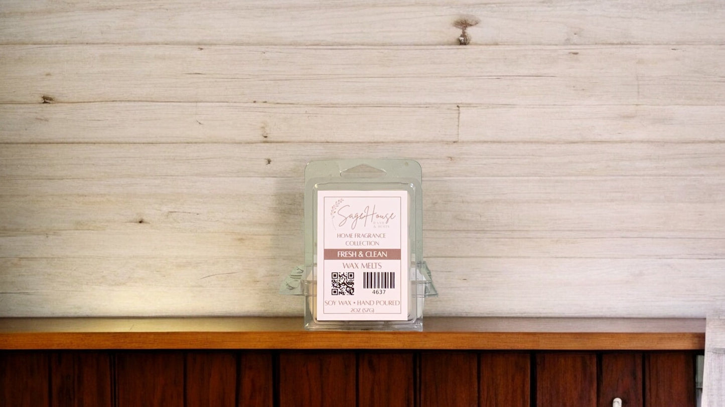 A clear clamshell container holding 6 wax melt cubes with a label on top, placed on a wooden surface against a wooden background.