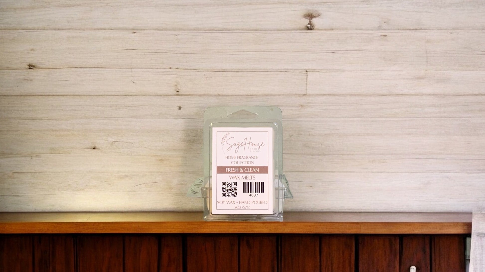 A clear clamshell container holding 6 wax melt cubes with a label on top, placed on a wooden surface against a wooden background.