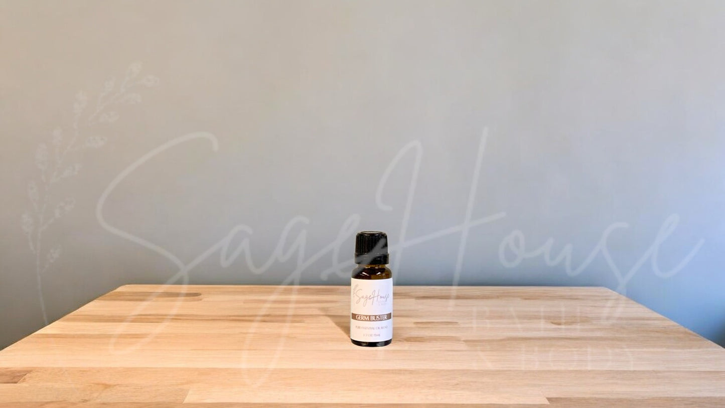 A small bottle of germ buster essential oil is placed on a wooden surface with a plain background.