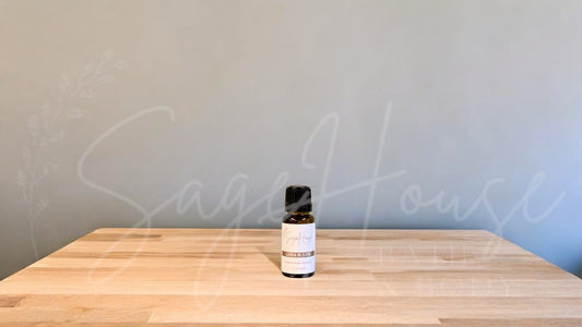 A small bottle of germ buster essential oil is placed on a wooden surface with a plain background.