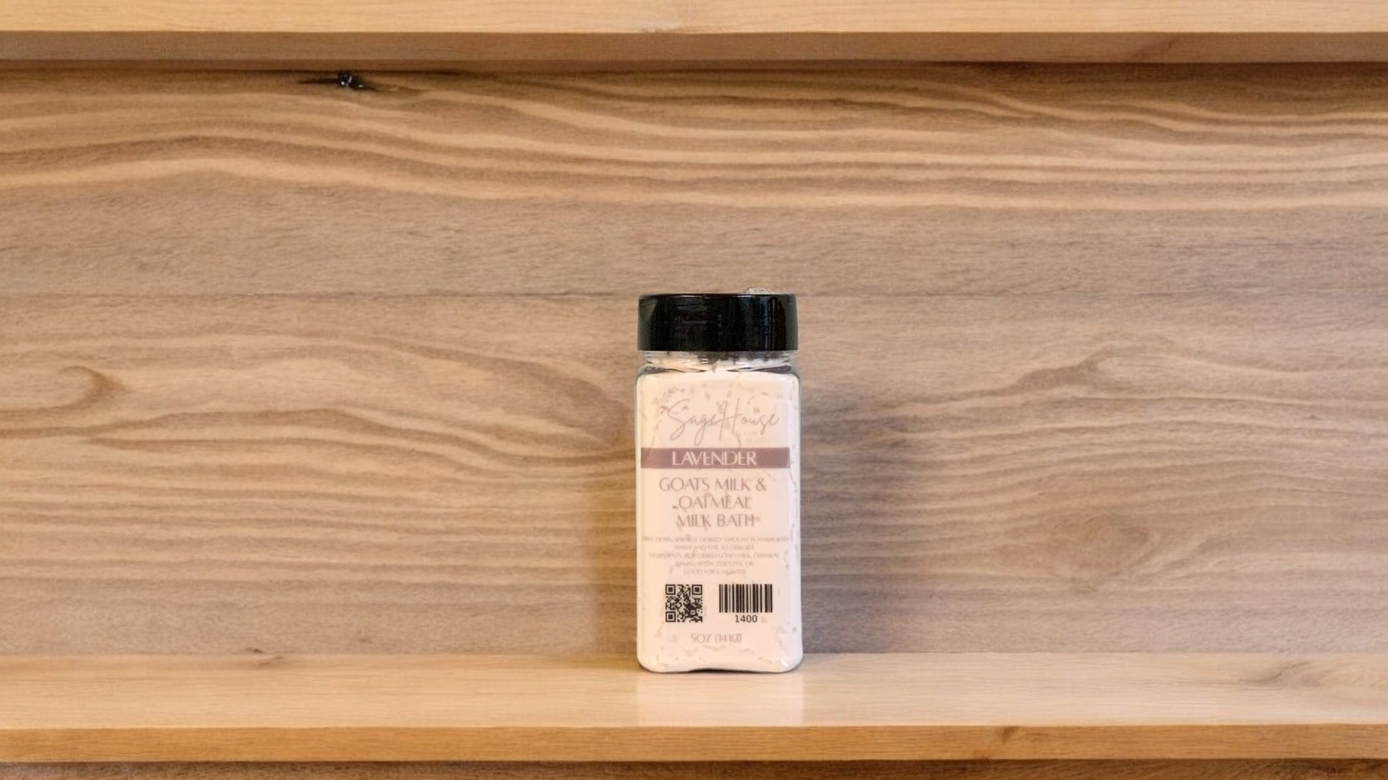 A clear spice jar with beige colored milk bath with black lid. with wood background
