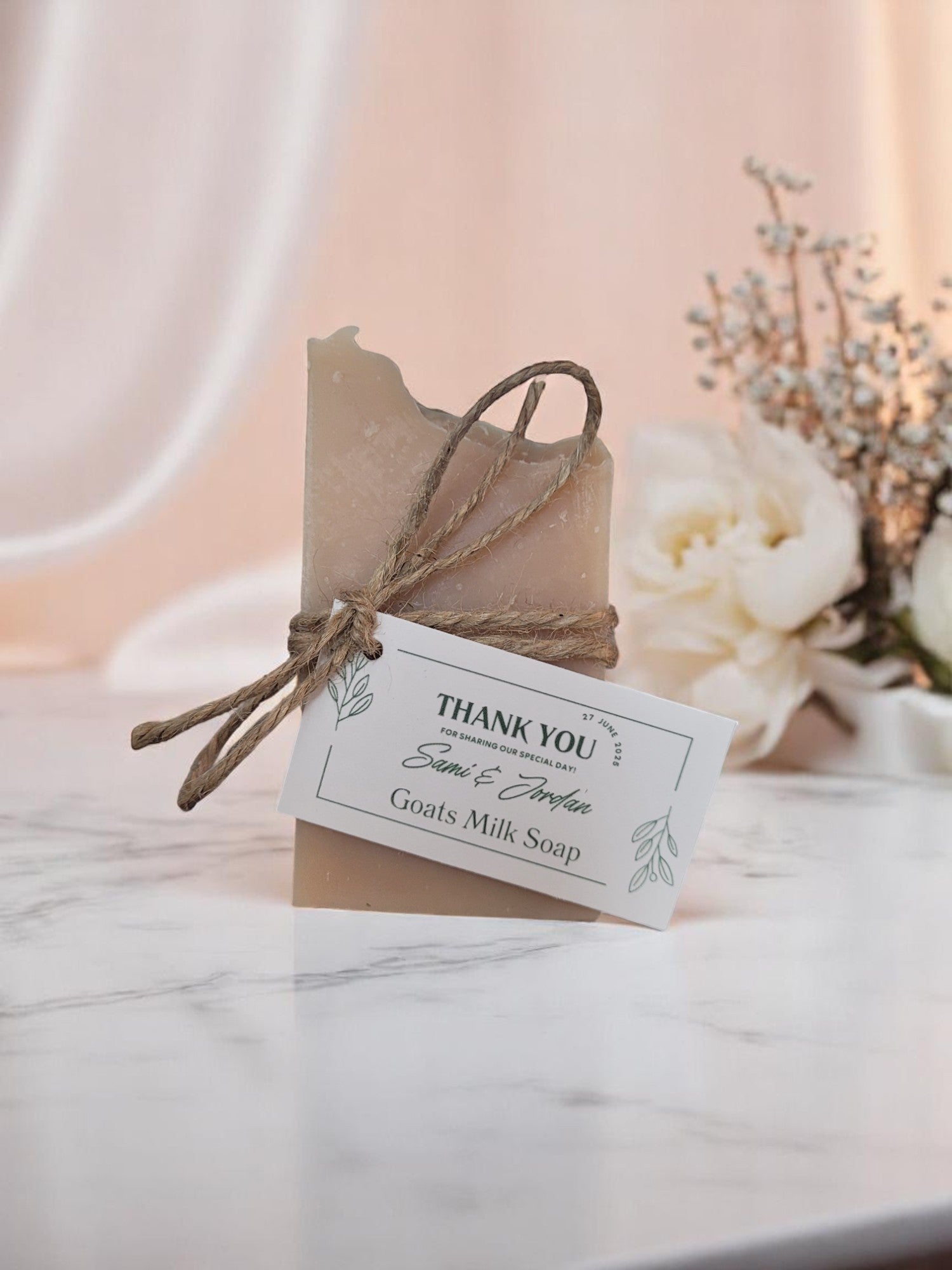Goats milk soap wrapped in brown paper with a 'Thank You' tag on a marble surface.