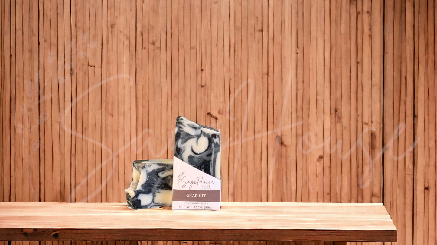 A white bar of soap with accents of black and gray in a white labeled box, on a wood surface.