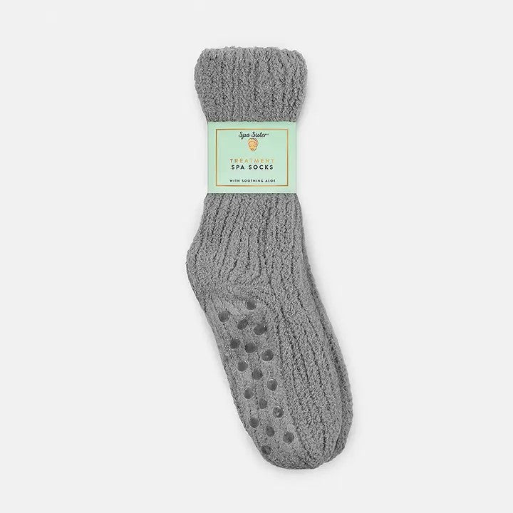 A pair of gray fuzzy spa socks with floor grippers and a label.