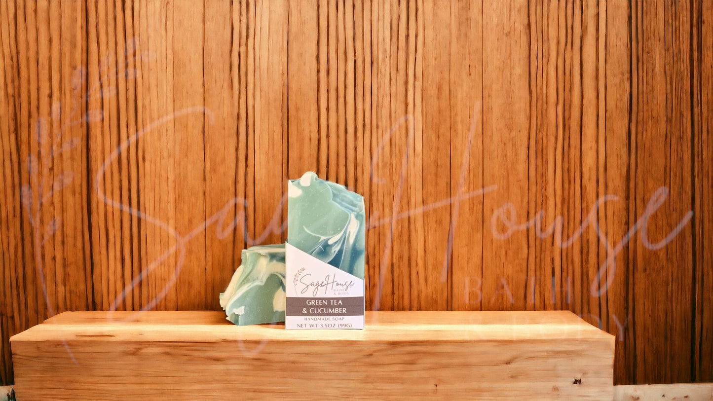 A light green colored bar of soap with dark green and white accents, in a white labeled box, on a wood surface.