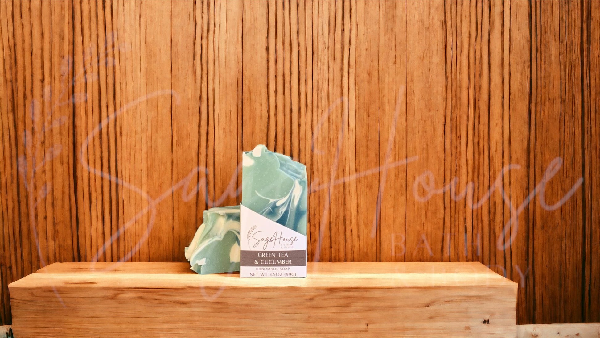 A light green colored bar of soap with dark green and white accents, in a white labeled box, on a wood surface.